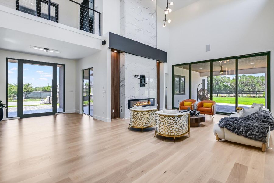 Living area with a high ceiling, a marble fireplace, and wood finished floors Living area with a high ceiling, a marble fireplace, and wood finished floors