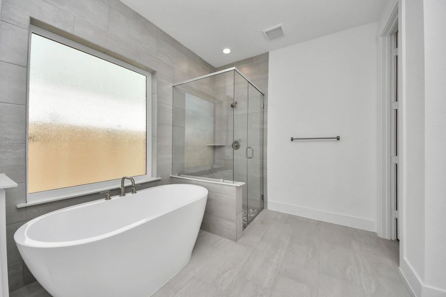 Indulge in a spa-like retreat within the confines of this primary bathroom. Delight in a spacious walk-in shower enveloped in stylish tile surround, unwind in a separate garden tub adorned with custom detailing.
