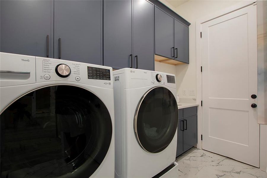 Washroom featuring light marble finish floors, cabinet space, and washer and clothes dryer Washroom featuring light marble finish floors, cabinet space, and washer and clothes dryer