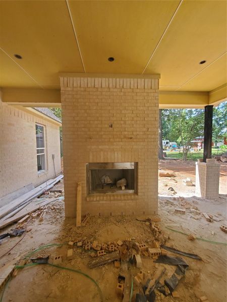 OUTDOOR FIREPLACE WRAPPED WITH WHITE BRICH BRICK WITH AN ELECTRICAL OUTLET ABOVE FOR TV INSTALLATION AND STEEL RODS FOR A FUTURE MANTEL (NOT PROVIDED BY BUILDER)