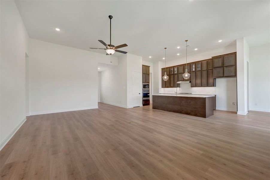Expansive living space featuring wood-finish flooring, recessed lighting, and a ceiling fan Expansive living space featuring wood-finish flooring, recessed lighting, and a ceiling fan