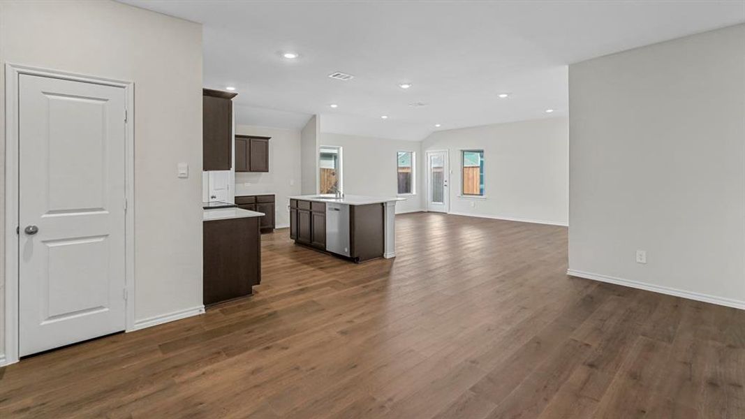 Kitchen featuring open floor plan, dark wood finish cabinets, a kitchen island with sink, recessed lighting, and dishwasher