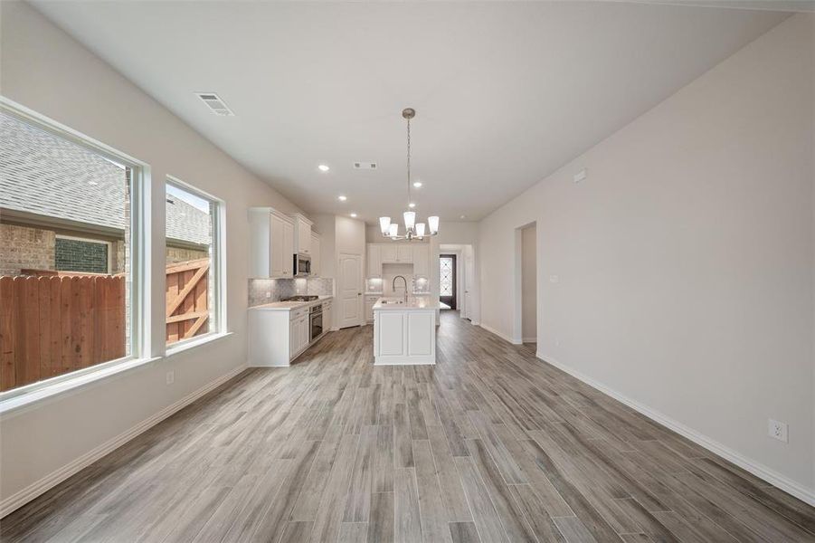 Unfurnished living room featuring a chandelier, light wood-style flooring, and recessed lighting