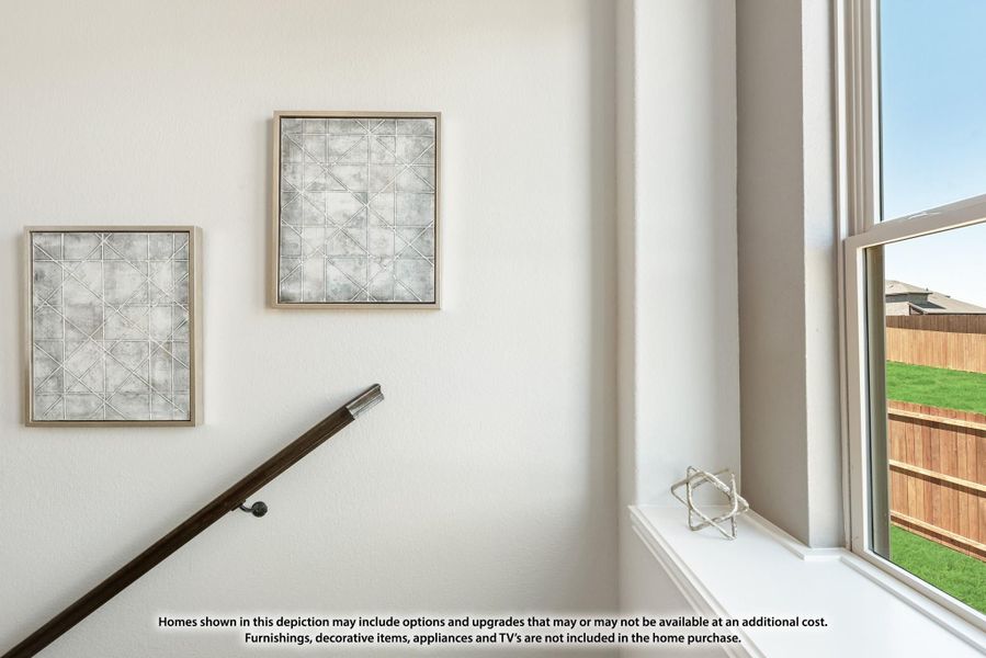 Stairway landing with two framed wall art pieces, wood handrail, and large window overlooking backyard Stairway landing with two framed wall art pieces, wood handrail, and large window overlooking backyard
