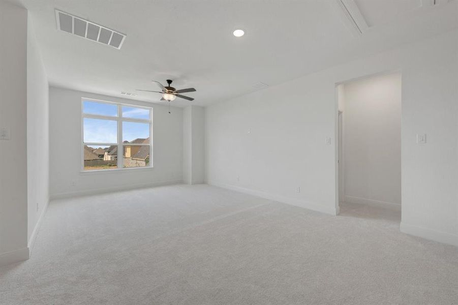 Spacious room featuring light-colored carpeting, white wall finishes, and a multi-pane window
