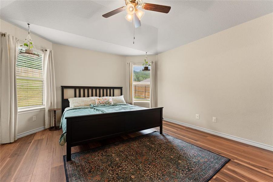 Bedroom with multiple windows, wood finished floors, and ceiling fan