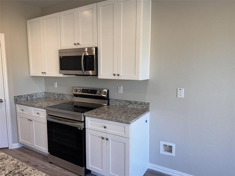 Kitchen with white cabinetry and appliances with stainless steel finishes