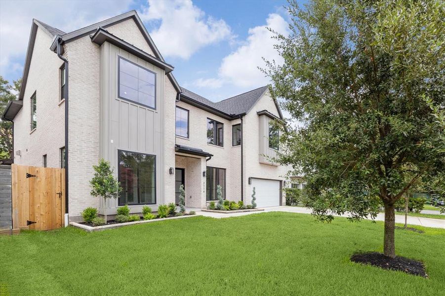 Front elevation with landscaping and two live oaks.