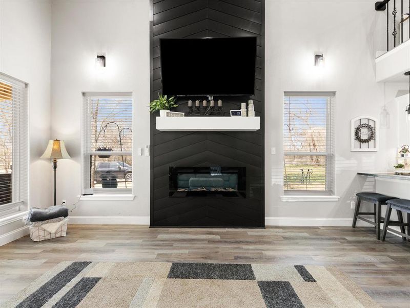 Living area with a high ceiling, wood finished floors, and baseboards