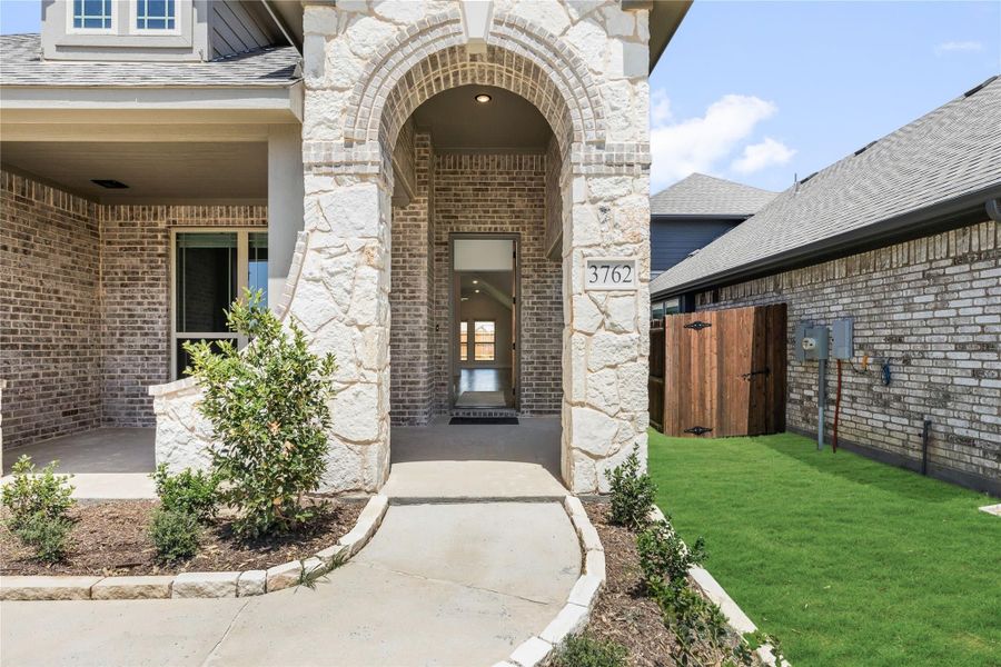 Home entrance with stone archway, brick exterior, and concrete walkway leading to front door Home entrance with stone archway, brick exterior, and concrete walkway leading to front door