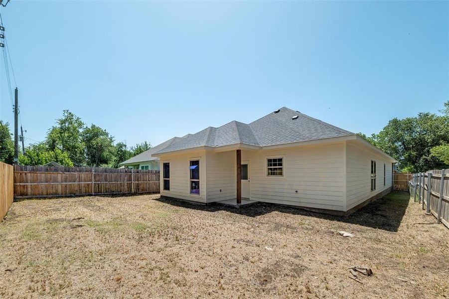 Back of house featuring roof with shingles and a fenced backyard