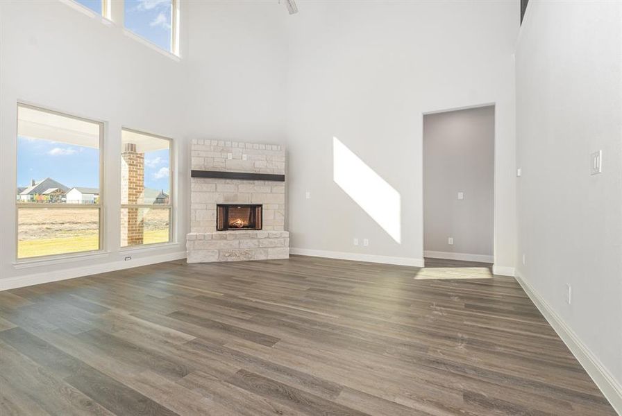 Unfurnished living room with a towering ceiling, dark wood-style flooring, and a fireplace