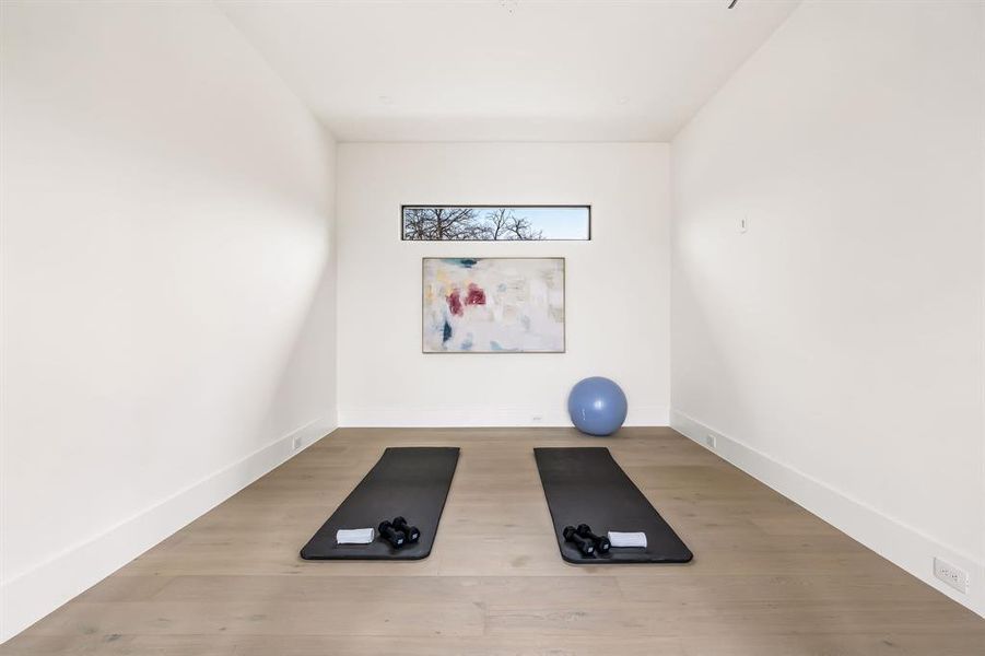 Exercise area featuring light wood finished floors and baseboards