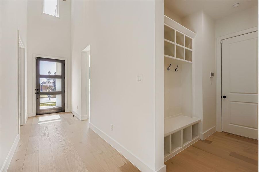 Mudroom with light wood-style flooring and a towering ceiling