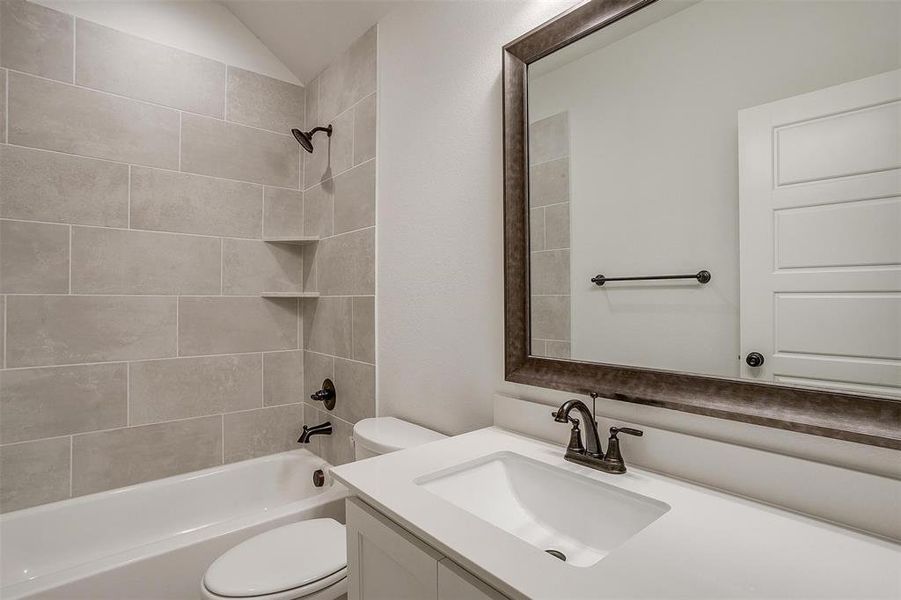 Full bathroom with tiled shower / bath combo, toilet, and vanity