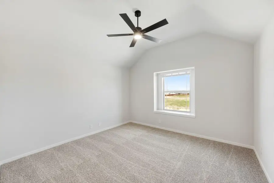 Empty bedroom with vaulted ceiling, black ceiling fan, carpet flooring, and single window with outdoor view