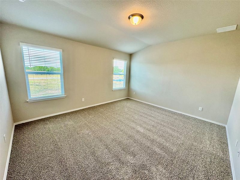 Spare room featuring carpet flooring, lofted ceiling, and a textured ceiling