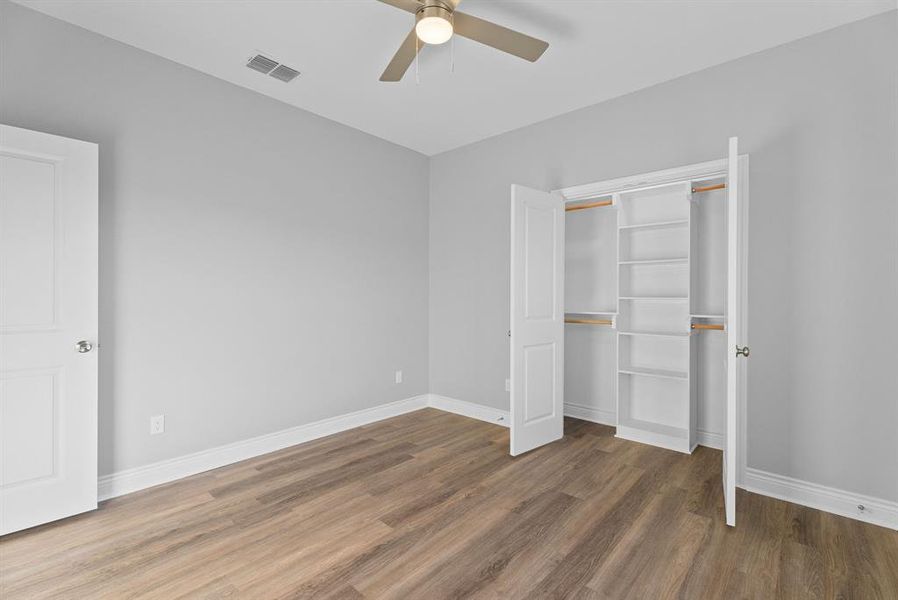 Unfurnished bedroom with dark wood-type flooring, a ceiling fan, and a closet