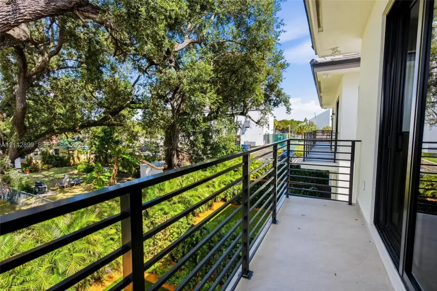 Covered balcony featuring concrete flooring and a black horizontal metal railing