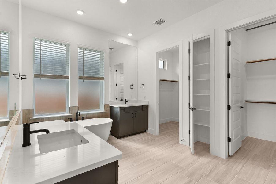 Full bath with a spacious closet, two vanities, a freestanding bath, and recessed lighting Full bath with a spacious closet, two vanities, a freestanding bath, and recessed lighting
