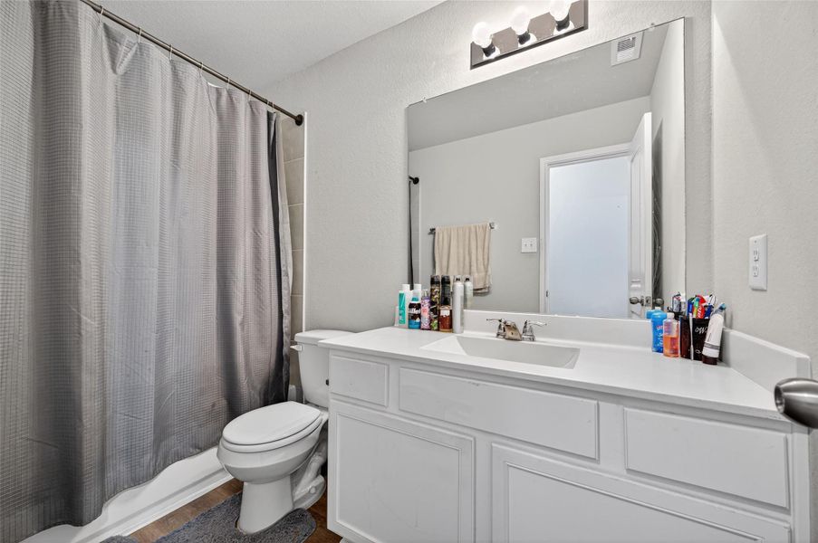 This bathroom features a modern design with a large mirror, ample counter space, and a single sink. It has a bathtub with a shower curtain and neutral-colored walls, creating a clean and inviting atmosphere.