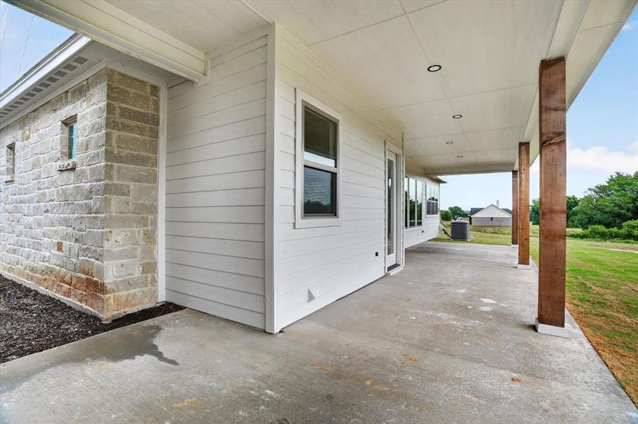 Expansive covered concrete patio featuring recessed lighting and robust wood pillars