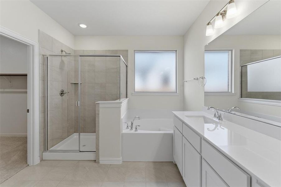 Full bathroom with vanity, a garden tub, a spacious closet, a stall shower, and light tile patterned flooring