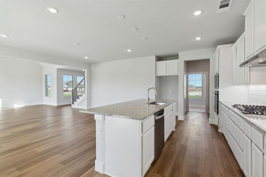 Kitchen featuring a healthy amount of sunlight, sink, stainless steel appliances, light hardwood / wood-style flooring, and a center island with sink