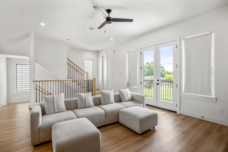 Back inside, the expansive living area is bathed in natural light from multiple oversized windows, creating an inviting atmosphere for relaxation, conversation, or cozy movie nights.