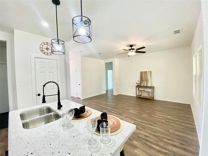 Kitchen featuring hanging light fixtures, ceiling fan, hardwood / wood-style floors, and light stone countertops