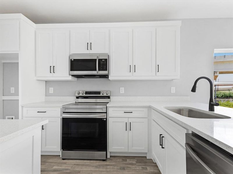 Kitchen featuring appliances with stainless steel finishes, a sink, light wood-style flooring, and white cabinets