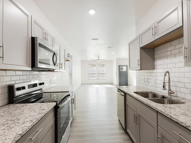 Kitchen with backsplash, appliances with stainless steel finishes, gray cabinetry, and recessed lighting