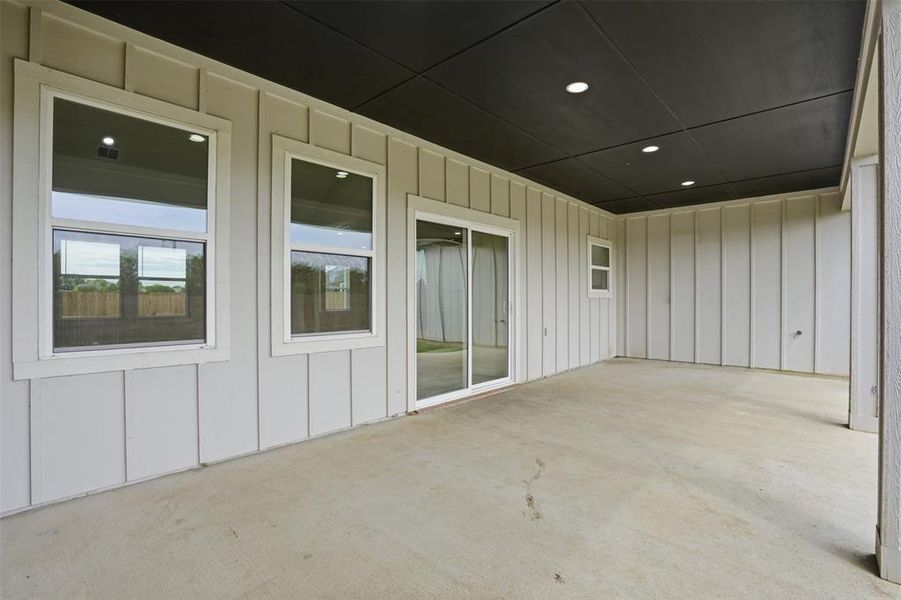 Covered patio with a concrete surface, featuring board and batten siding, recessed lighting, and a sliding glass door