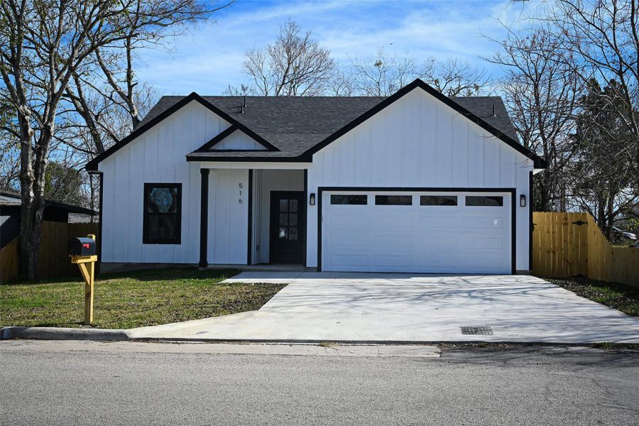 Modern inspired farmhouse with board and batten siding, driveway, roof with shingles, and an attached garage