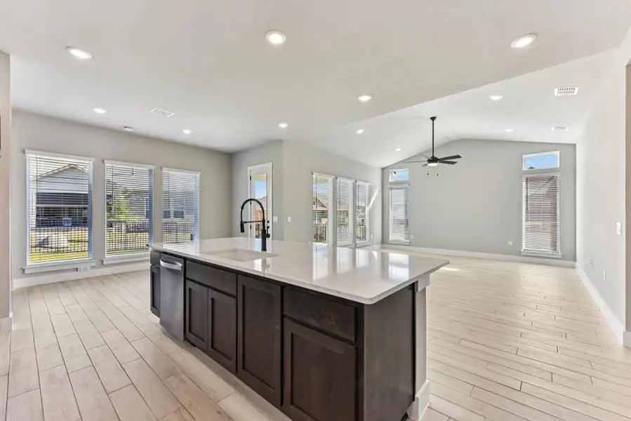 Kitchen with dark brown cabinets, open floor plan, recessed lighting, healthy amount of natural light, and vaulted ceiling