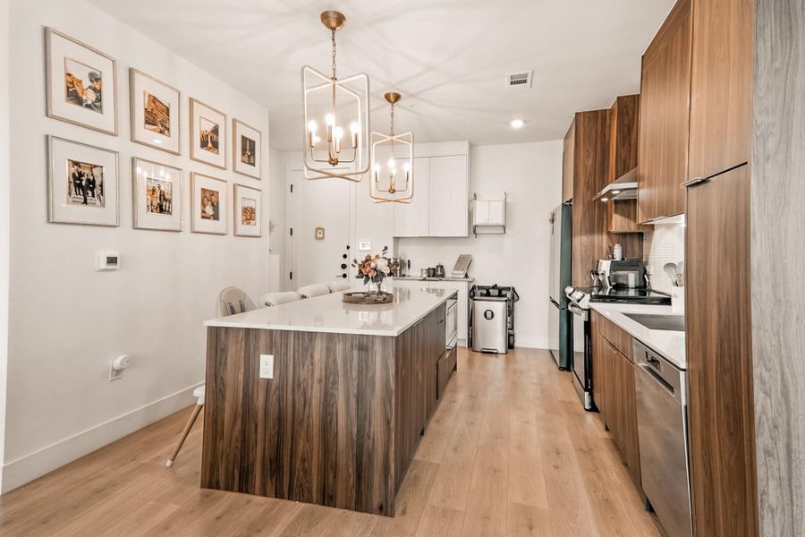 Kitchen with a kitchen island, a chandelier, light countertops, modern cabinets, and recessed lighting
