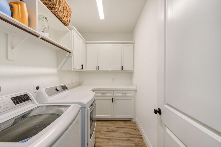 Laundry room with built-in cabinetry, folding space, and convenient upper shelving for organization