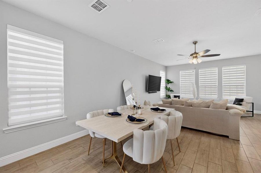 Open-plan living area featuring light-colored walls, tile flooring, and a ceiling fan
