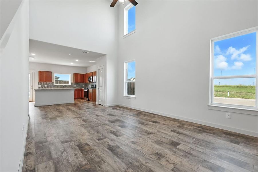 Unfurnished living room featuring a towering ceiling, dark wood-type flooring, and ceiling fan Unfurnished living room featuring a towering ceiling, dark wood-type flooring, and ceiling fan