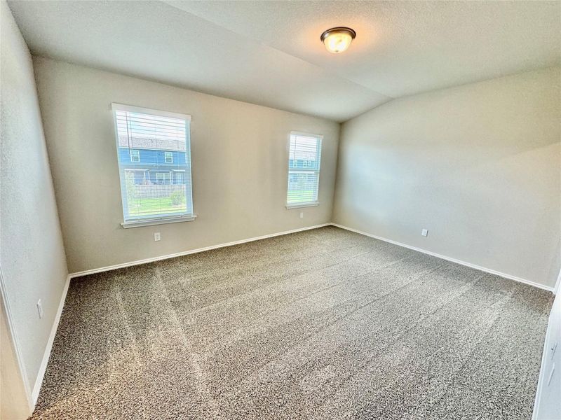 Carpeted spare room with vaulted ceiling and a textured ceiling