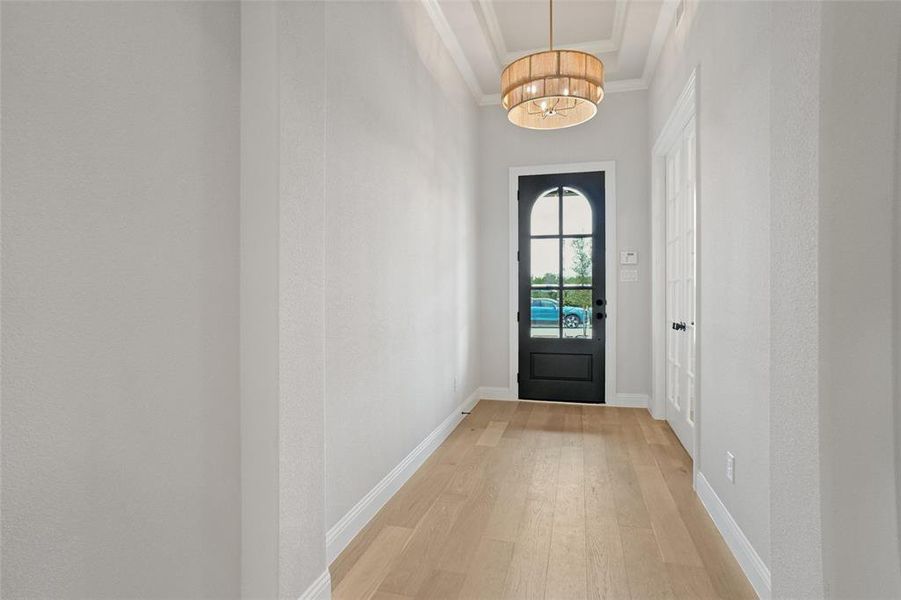 Entryway featuring light hardwood / wood-style flooring, a notable chandelier, and ornamental molding