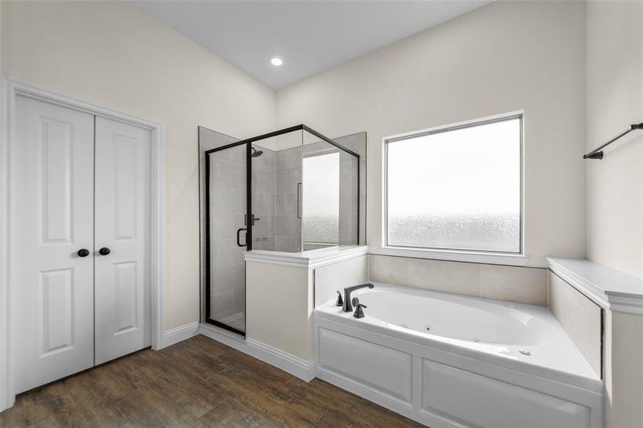 Bathroom featuring a corner soaking tub with dark bronze fixtures, a separate glass-enclosed shower with dark bronze framing, and wood-finish flooring