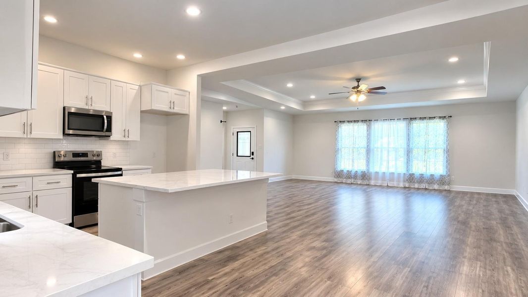 Step into a spacious open-concept living area featuring sleek floors, a modern kitchen with stainless steel appliances, and abundant natural light from large windows.