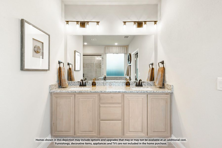 Bathroom with double sink vanity, granite countertops, light wood cabinets, and large mirror with overhead lighting