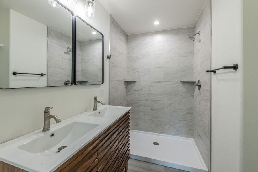 Modern bathroom featuring a dual vanity with wood-finish cabinetry and brushed nickel fixtures Modern bathroom featuring a dual vanity with wood-finish cabinetry and brushed nickel fixtures