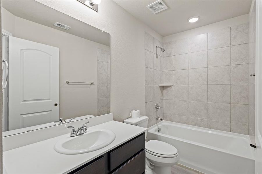 Full bathroom with shower combination, vanity, and a textured wall Full bathroom with shower combination, vanity, and a textured wall