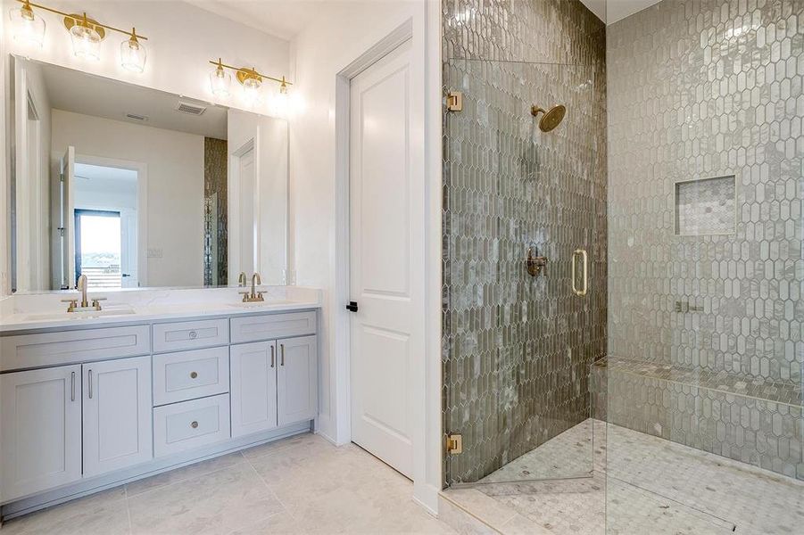 Bathroom with a sink, a stall shower, double vanity, and tile patterned floors