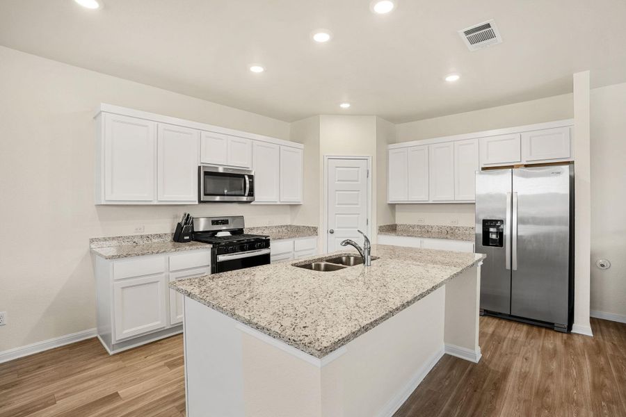 Sleek stainless steel appliances complement the bright white cabinetry and granite countertops in this functional kitchen.