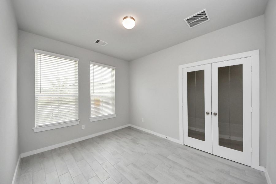 Experience the perfect blend of sophistication and warmth in this home office, boasting elegant wood-look tile flooring and flooded with natural light from expansive windows and French doors. Sample photo of completed home with similar floor plan. Actual colors and selections may vary. Experience the perfect blend of sophistication and warmth in this home office, boasting elegant wood-look tile flooring and flooded with natural light from expansive windows and French doors. Sample photo of completed home with similar floor plan. Actual colors and selections may vary.