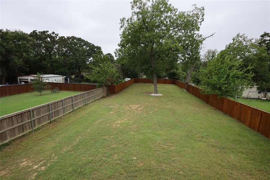 Fenced backyard with view of wooded area